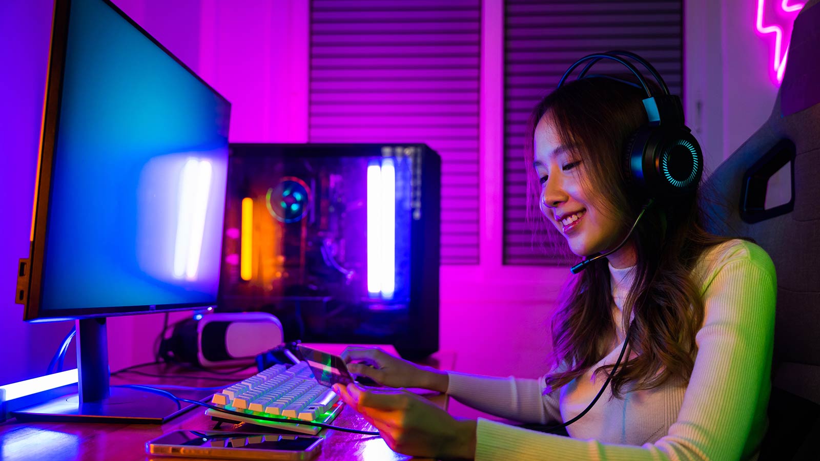 Happy young Asian woman gamer wearing headphones she smile holding card account after pay game online, female enjoying using credit card playing gaming with money