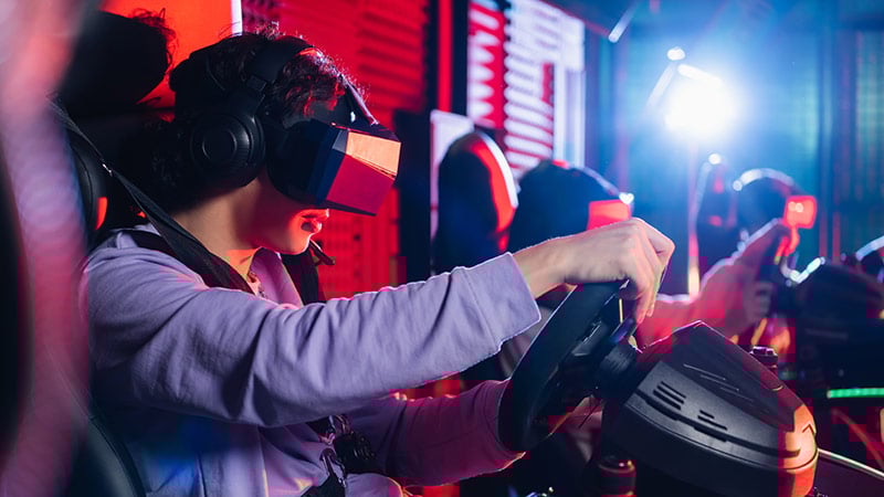 Teenage boy in VR headset playing racing game on car simulator