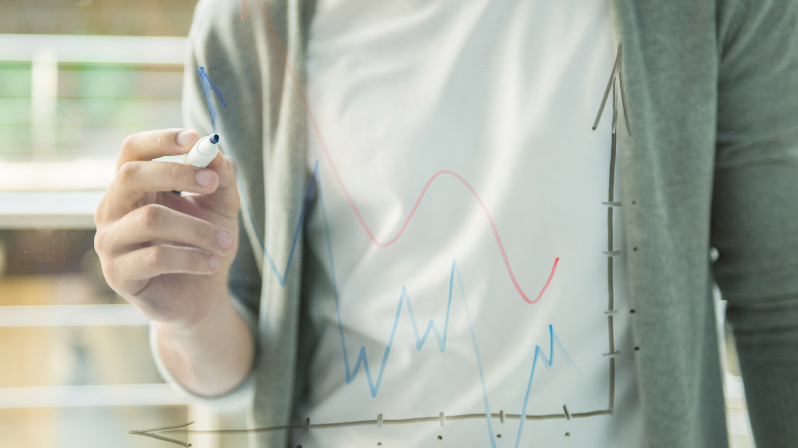 Man drawing chart on glass idea board.
