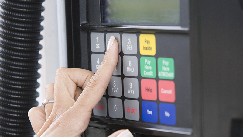 Woman paying at gas pump.