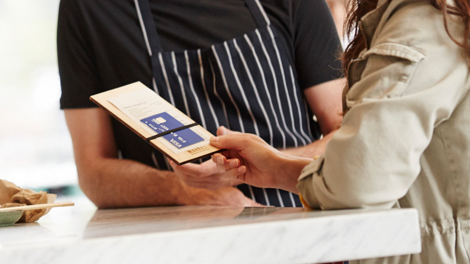 Woman offering Visa card with tab to waiter at restaurant.