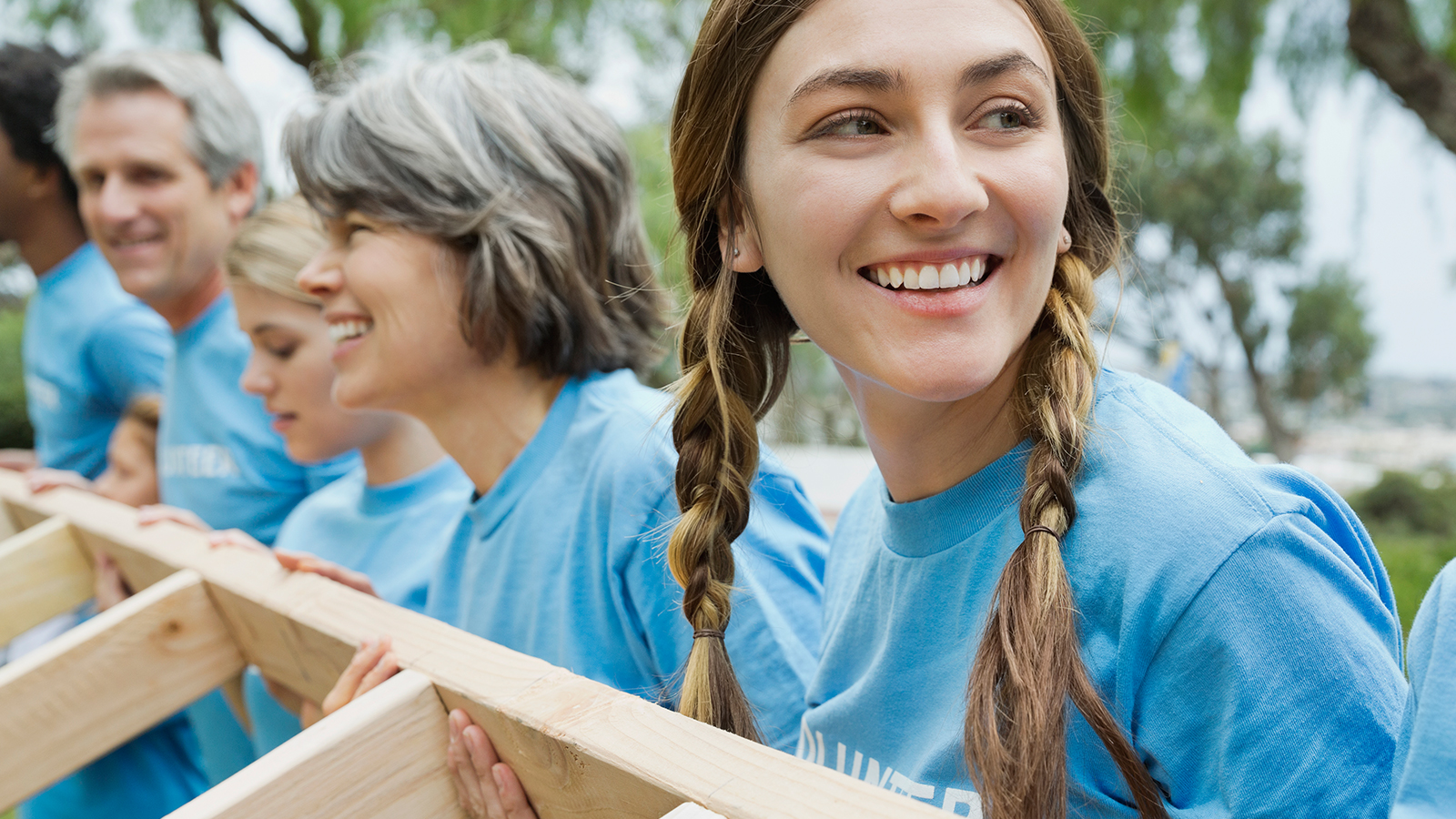 A group of volunteers working together to hoist a wall stud.