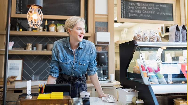 Retailer behind front counter in her shop. Retailer behind front counter in her shop.