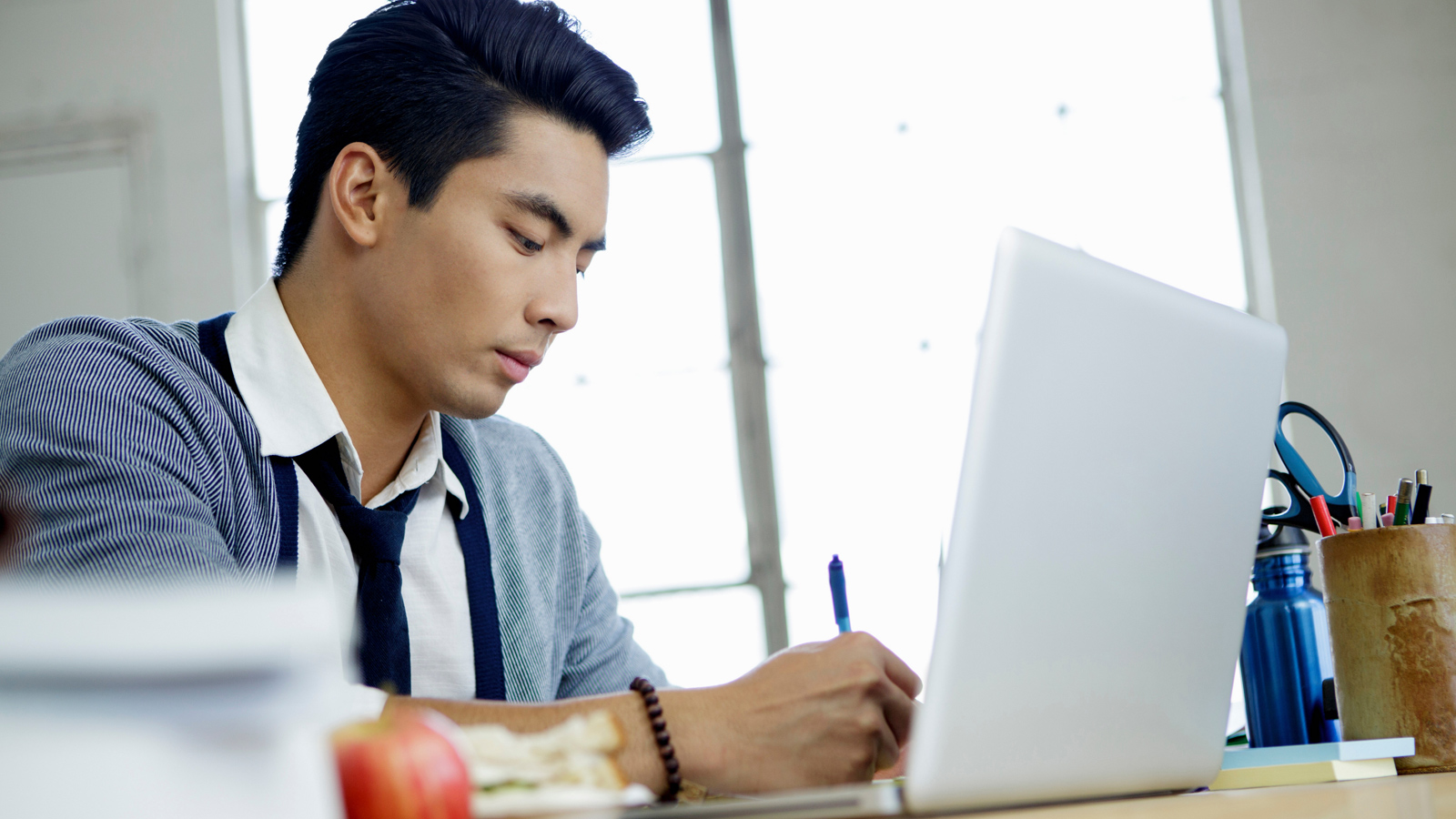 Young man sitting at his desk and working in front of his laptop. Young man sitting at his desk and working in front of his laptop.