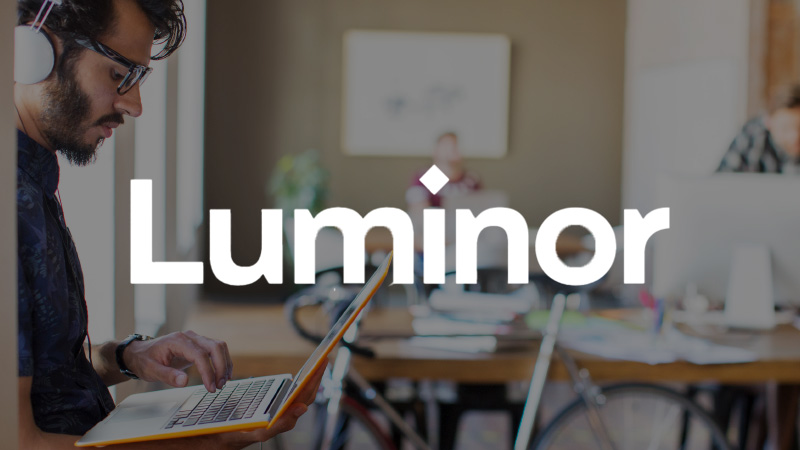 Luminor logo overlaying imagery of a man on his laptop.