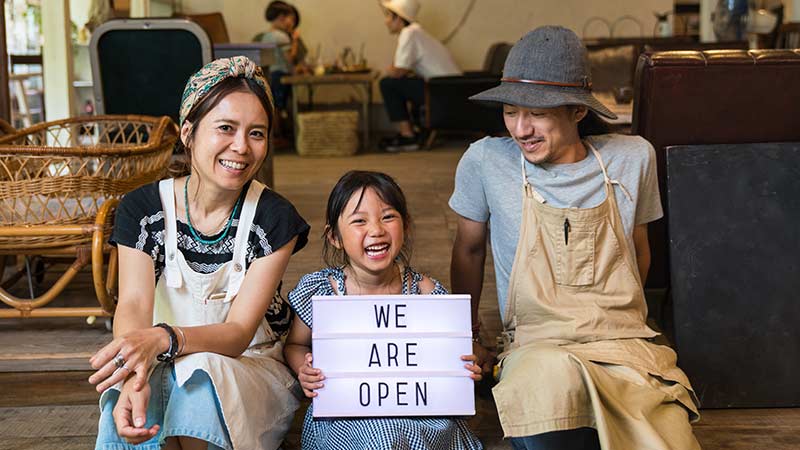 A photo of three family members with the sign that encourages individuals to buy from them as a small business support.