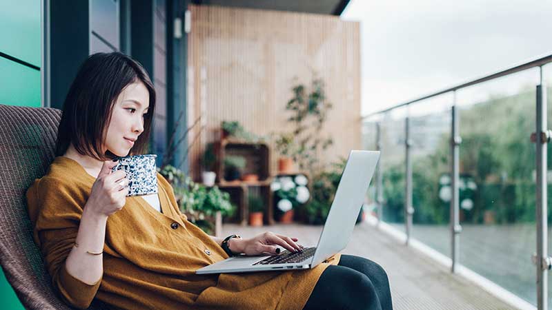 lady sipping tea while using a laptop
