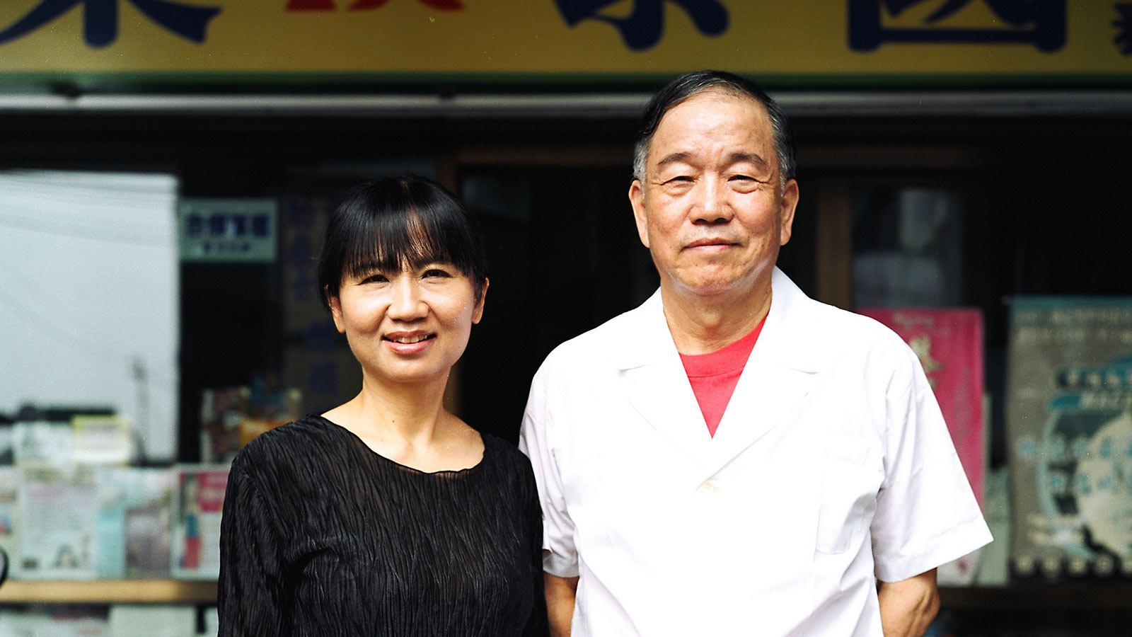 asian couple standing infront of a storefront
