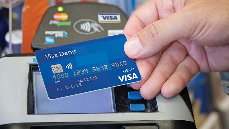 An image of a hand holding a Visa debit card.