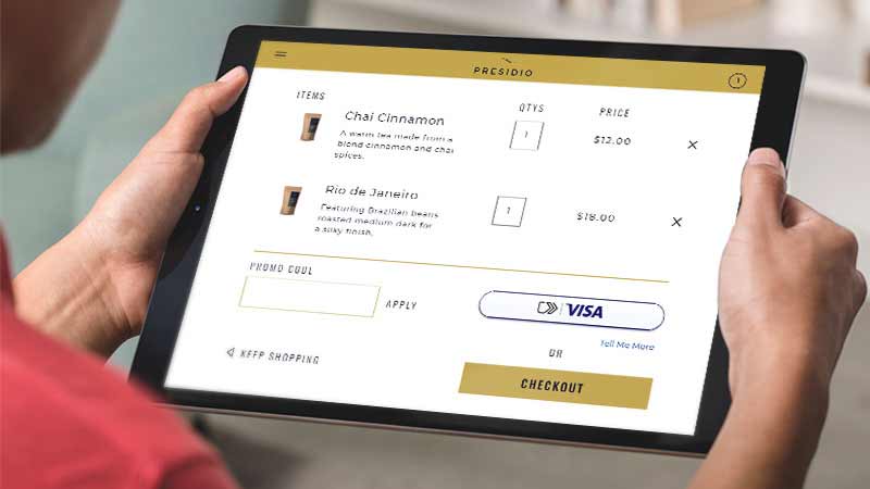 An individual using a tablet to make a payment for coffee with the 'click to pay' feature.